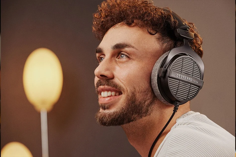 Person mit aufgesetztem beyerdynamic DT 990 PRO vor warmem Hintergrund
