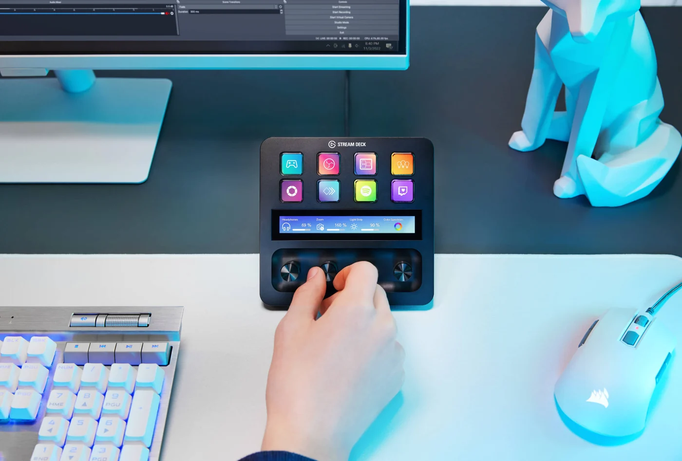 Elgato Stream Deck + auf einem Schreibtisch, eine Hand bedient einen der vier Drehregler