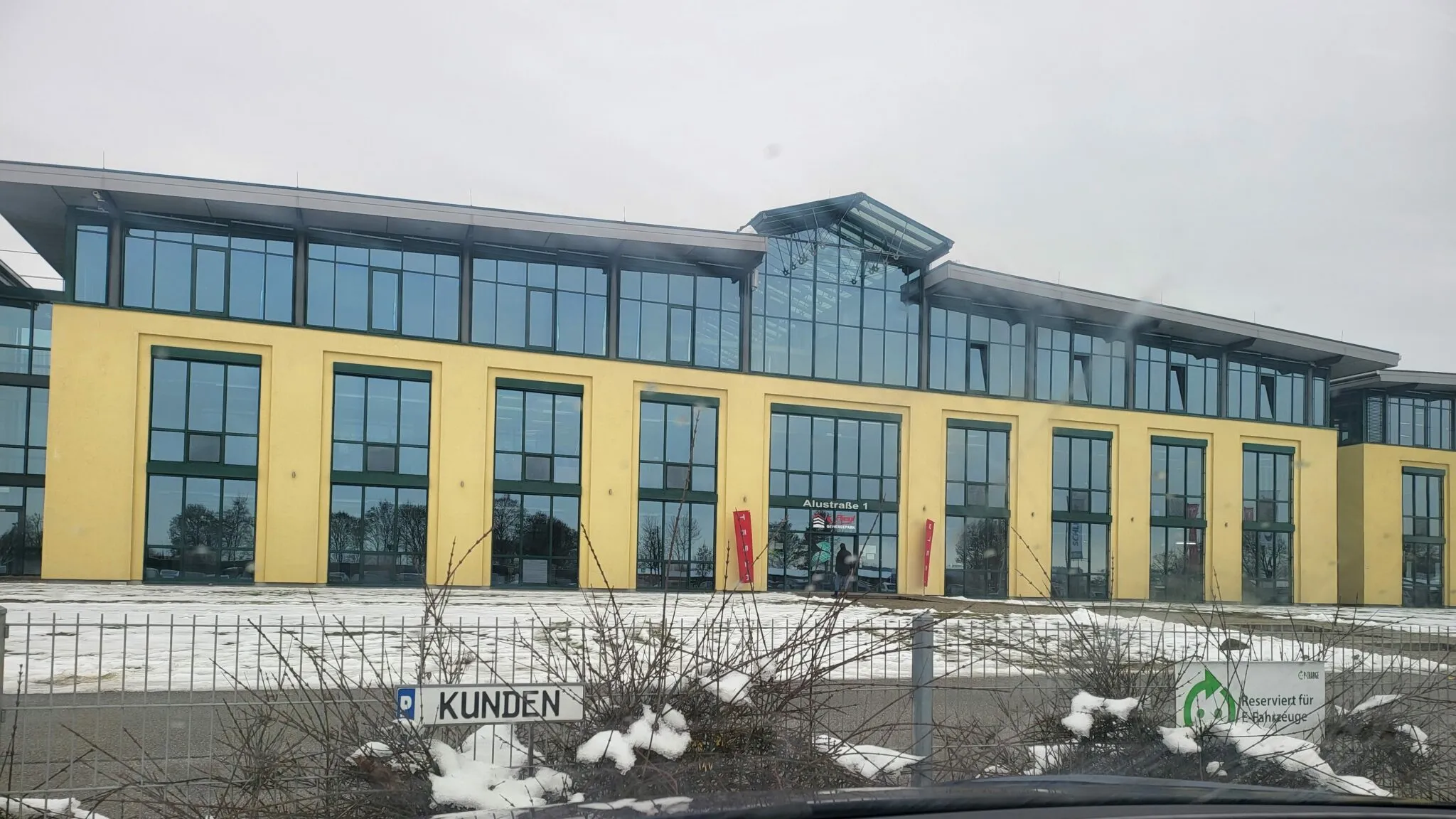 Gelbes Gebäude des Tesla-Auslieferungszentrums in Haag-Kirchdorf mit Kundeneingang im Winter