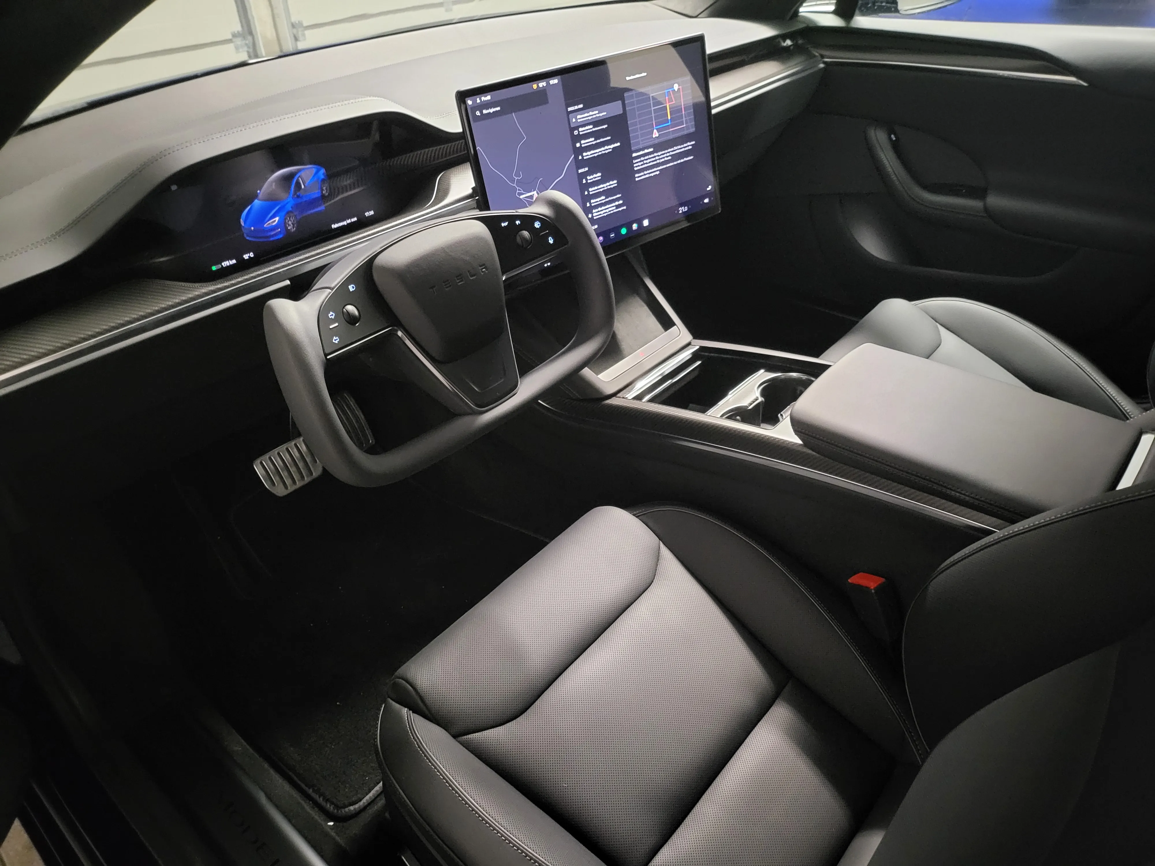 Innenraum des Model S Plaid mit Yoke-Lenkrad, Mitteldisplay und schwarzen Vordersitzen