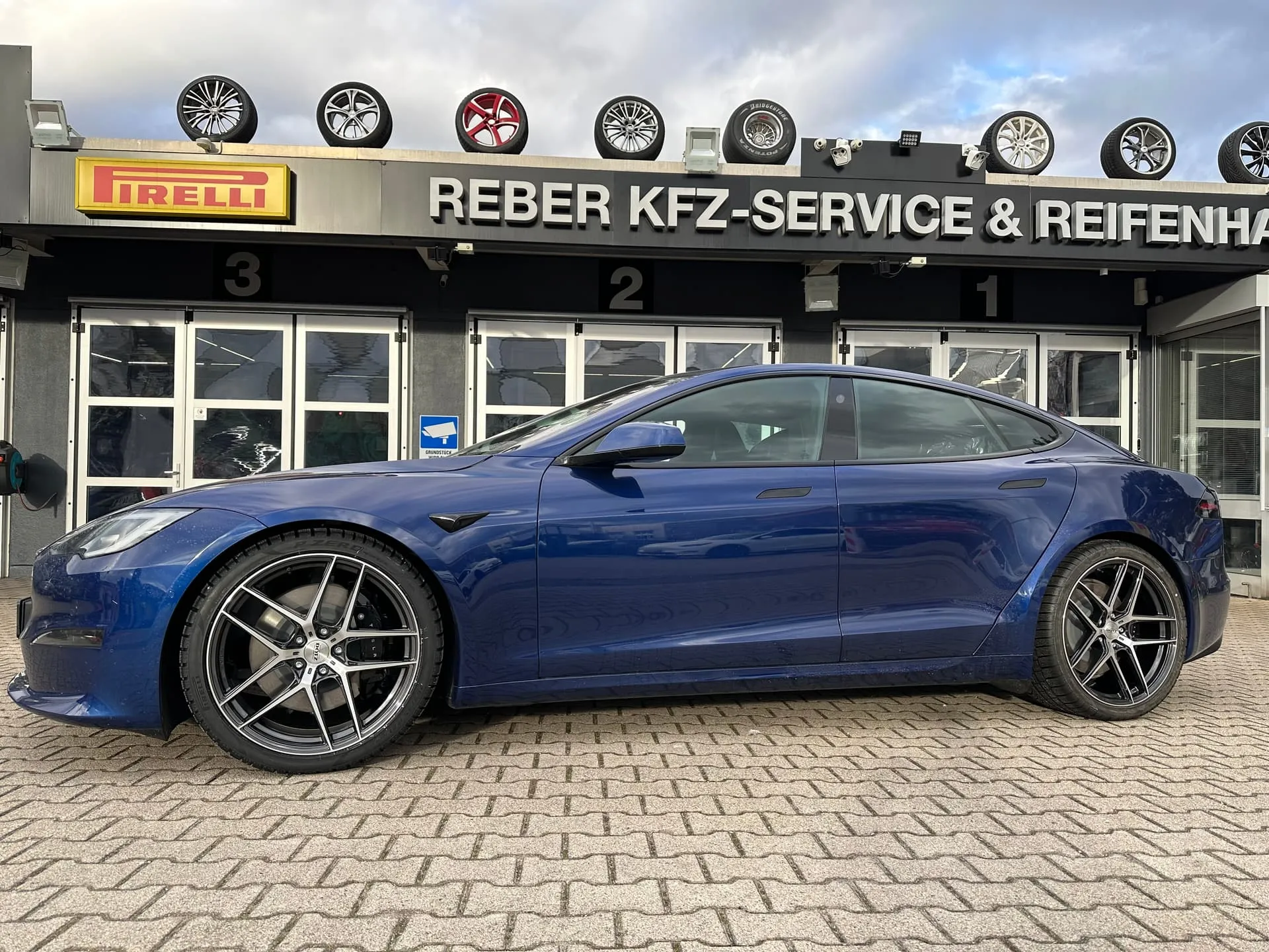 Blaues Tesla Model S Plaid auf 21-Zoll-DOTZ-Felgen vor dem Reifenhaus Reber